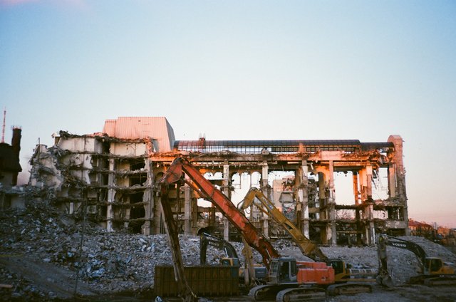 Excavator in front of a demolished building